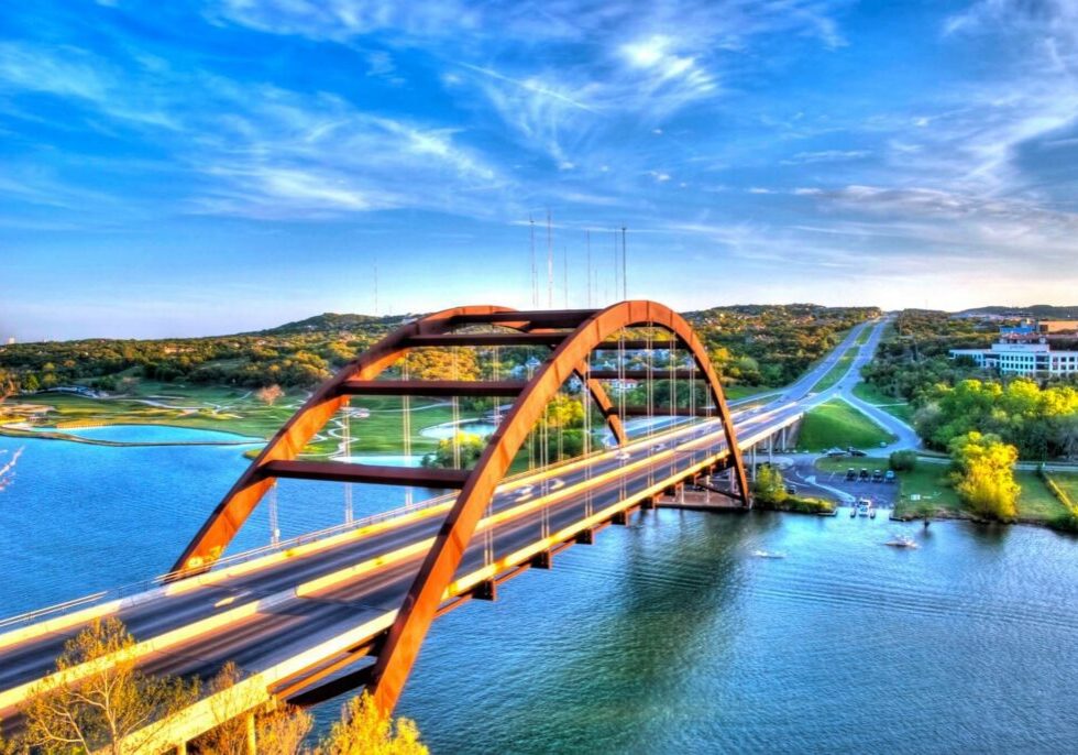 Orange arched bridge over river with roadway